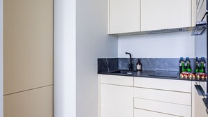 Een moderne keuken met witte kastjes, een zwart aanrecht en een houten vloer.
