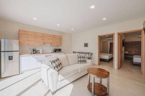 A modern apartment with a kitchenette, a sofa, a coffee table, and a bed in the adjacent room. - Super Stylish Home with Private Pool and outdoor (Noord)