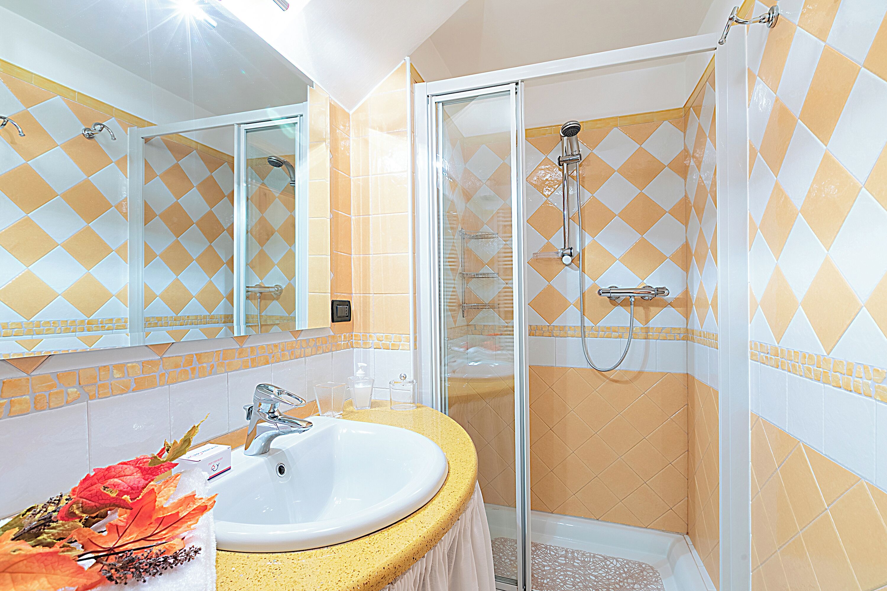 A bathroom with a sink, mirror, shower, and decorative elements.