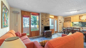 A living room with a sofa, a television, and a stone wall. - Appartamento I 2 Pini for 6 With Balcony (Sauze d'Oulx)