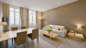 A modern living room with a sofa, coffee table, and dining table. - 2 bedroom apartment - Rue Macé - 1mn Plage Croisette & Palais (Cannes)