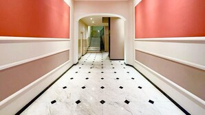 A hallway with a marble floor, red walls, and a staircase in the distance. - 2 bedroom apartment - Rue Macé - 1mn Plage Croisette & Palais (Cannes)