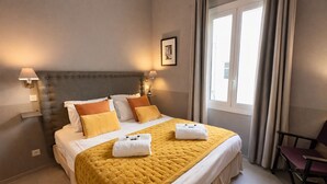 A hotel room with a bed, two bedside lamps, a chair, and a window with curtains. - 2 bedroom apartment - Rue Macé - 1mn Plage Croisette & Palais (Cannes)