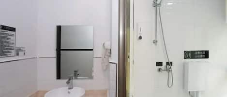 Une salle de bain moderne avec un lavabo blanc, un miroir et une douche séparée par des parois en verre.
