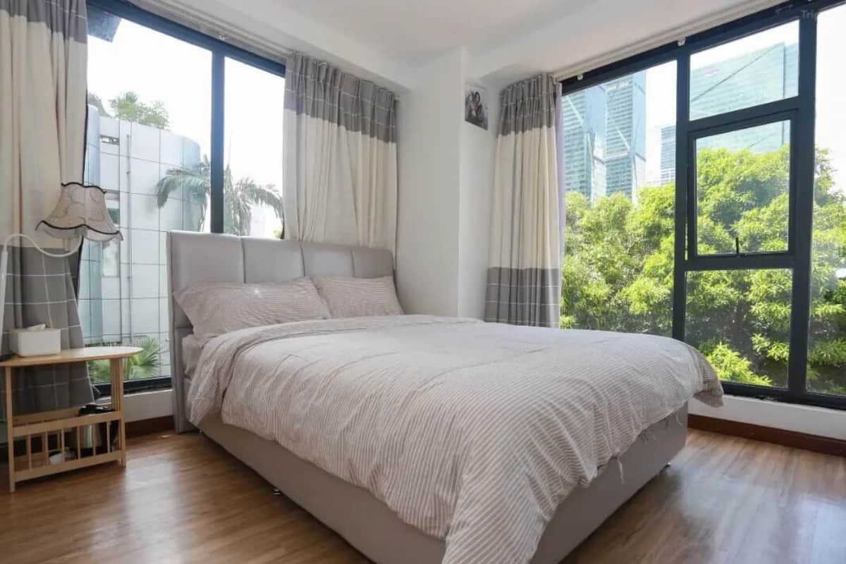 A bedroom with a large bed, a bedside table, and curtains.