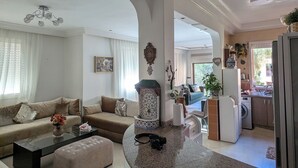 En rummelig opholdsstue med en buet granitbordplade, en sofasæt og et spiseområde.