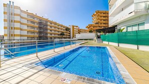 Una piscina con plataforma de baldosas, rodeada de edificios de varios pisos con balcones.