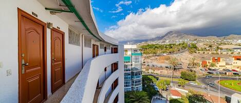 A hotel with a curved balcony overlooking a cityscape, including a road with cars and palm trees.