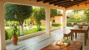 Une terrasse extérieure avec une table dressée pour le repas, entourée de verdure et offrant une vue sur un jardin.