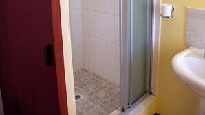 A bathroom with a glass shower enclosure, a white sink, and yellow walls. - Perfect 8-bedroom lodge in Mbabane for your group getaway (Mbabane)