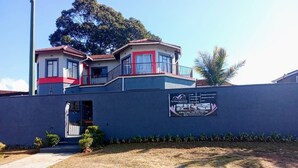 A two-story building with a balcony, a signboard, and a paved entrance. - Perfect 8-bedroom lodge in Mbabane for your group getaway (Mbabane)