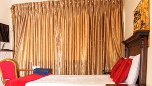A hotel room with a large bed, a red carpet, a wooden dresser, and a television on a stand. - Perfect 8-bedroom lodge in Mbabane for your group getaway (Mbabane)