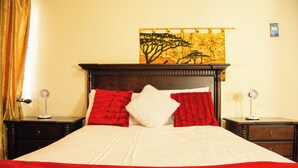 A neatly made bed with a red and white bedspread, two nightstands with lamps, and a painting on the wall. - Perfect 8-bedroom lodge in Mbabane for your group getaway (Mbabane)
