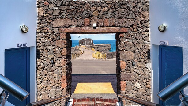 A stone archway leading to a coastal area with a view of the sea and a building labeled "DAVIDE". - Apartamentos Puntagrande - Unique experience in front of the Atlantic Ocean in El Hierro (Frontera)