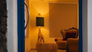 A room with a round, textured coffee table, a lamp with a giraffe figurine, and a tufted armchair with a red pillow. - Apartamentos Puntagrande - Unique experience in front of the Atlantic Ocean in El Hierro (Frontera)