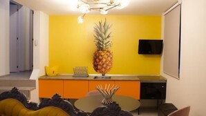 A modern kitchen with a yellow accent wall, a pineapple centerpiece, and a flat-screen TV. - Apartamentos Puntagrande - Unique experience in front of the Atlantic Ocean in El Hierro (Frontera)