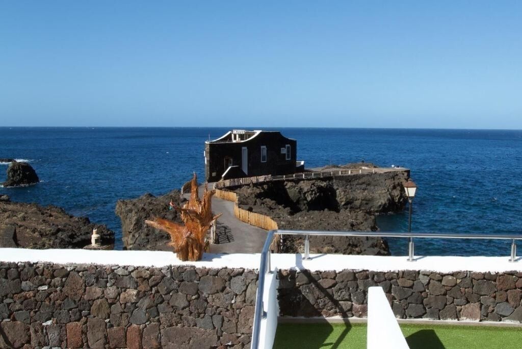 A coastal building with a stone wall and a wooden deck.