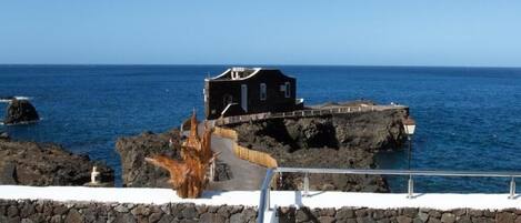 A coastal building with a stone wall and a wooden deck.