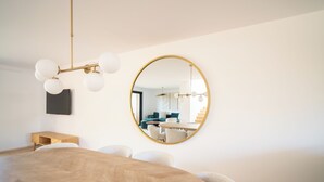 Ein modernes Schlafzimmer mit einem großen Bett, einem runden Spiegel, einer Chandelüster und einem Nachttisch aus Holz.