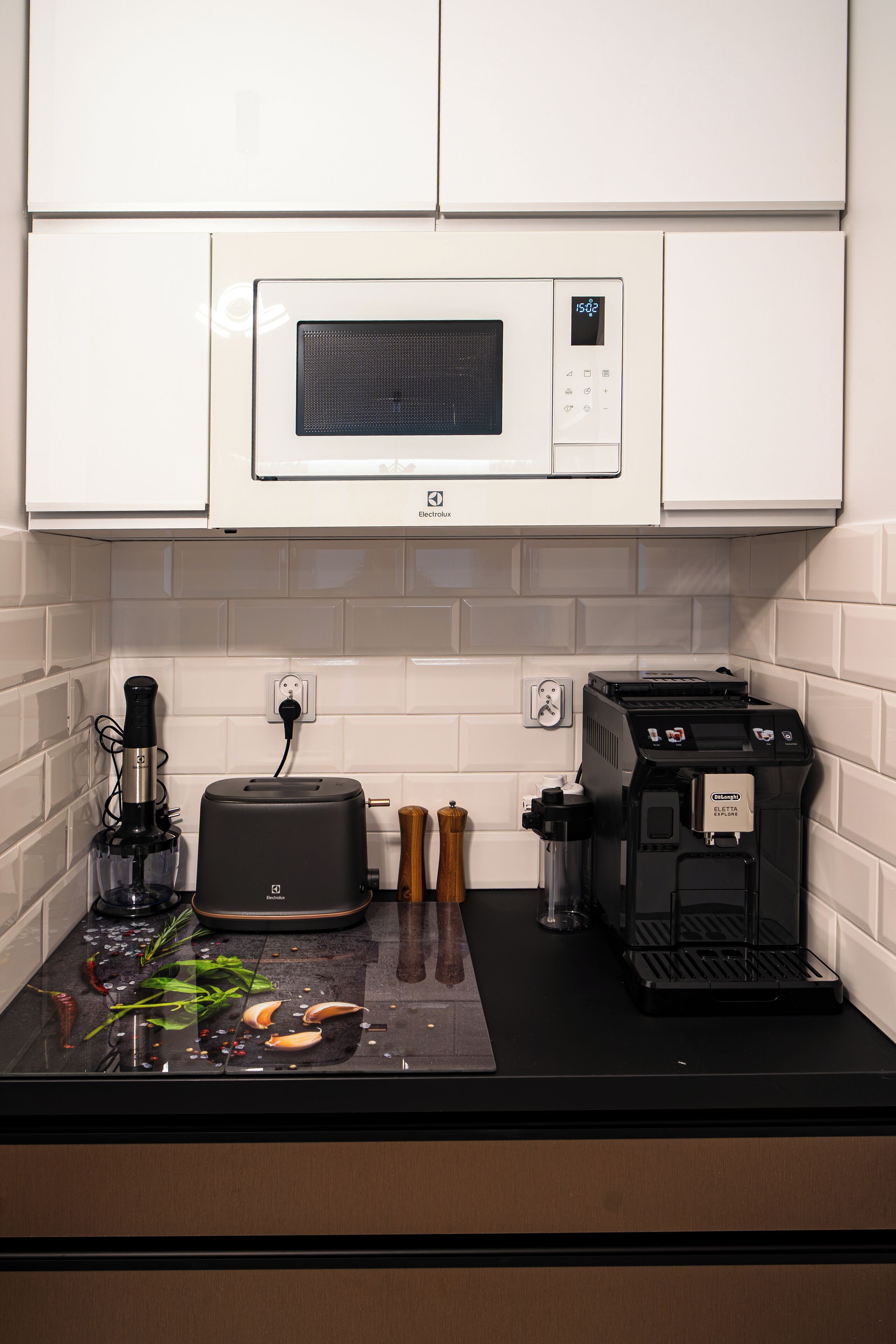 A kitchen with a microwave, toaster, coffee machine, and a blender on the counter.