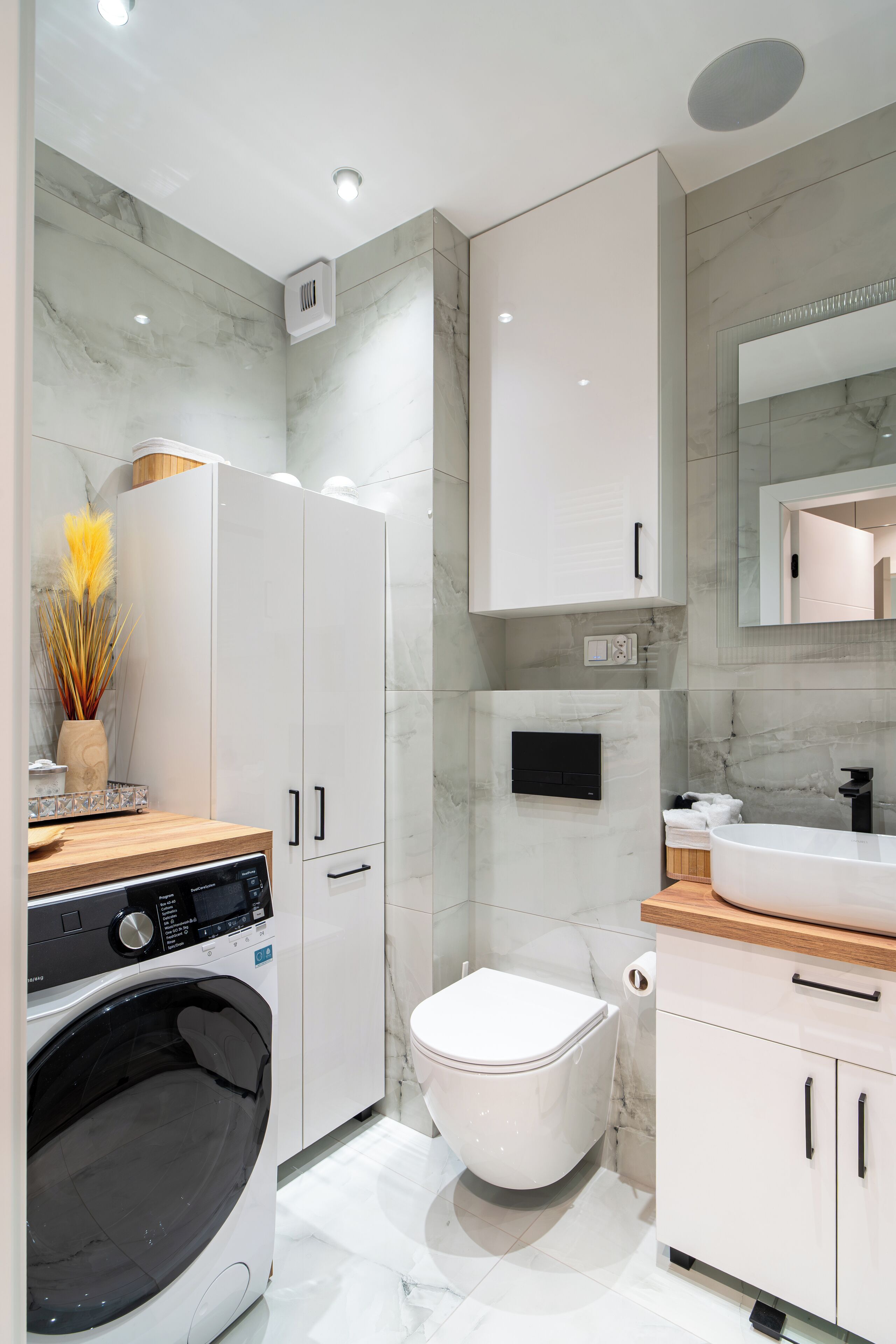 Un bagno moderno con lavatrice integrata, un water e un lavabo con specchio sopra.