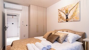 A bedroom with a bed, pillows, a painting, and a wardrobe. - ApartSanok - Apartament Widokowy 27-49 (Sanok)