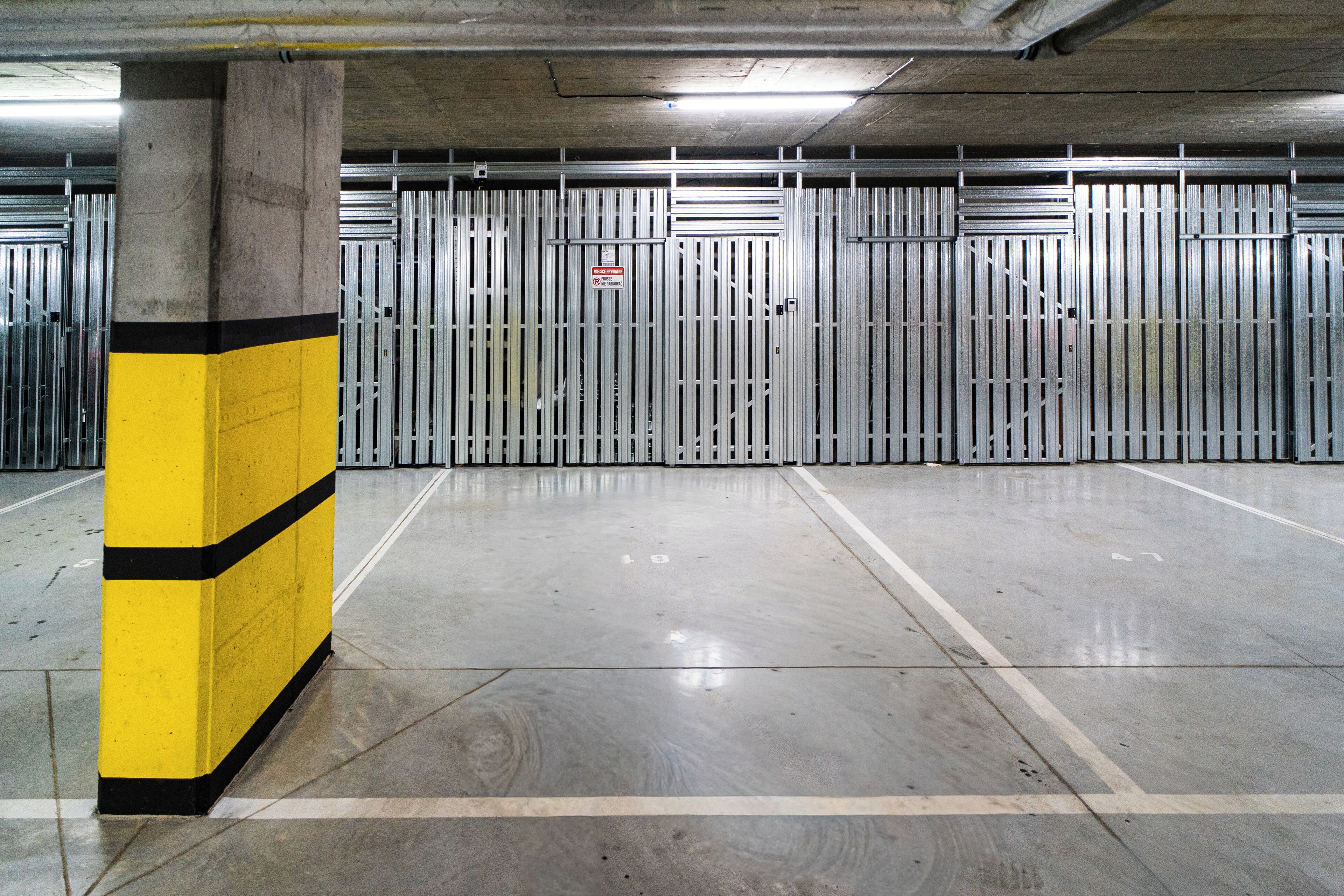 A parking garage with concrete pillars and metal barriers.
