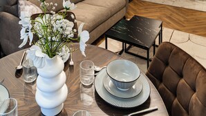 A modern living room with a sofa, dining table, and kitchen in the background. - ApartSanok - Apartament Widokowy 27-49 (Sanok)