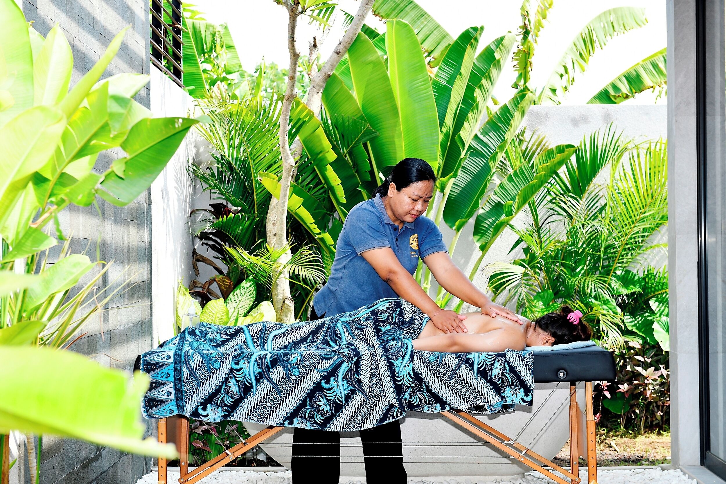 A massage therapy session in a tropical setting with a massage table, a client, and a therapist.