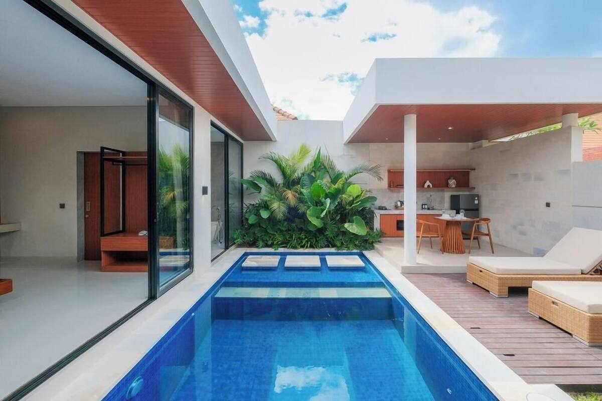 Ein moderner Poolbereich im Freien mit Küche und Lounge-Möbeln.