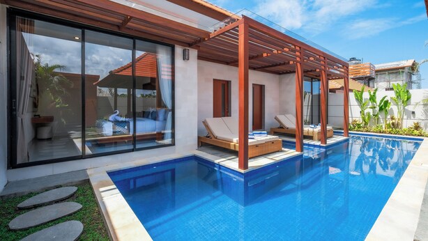 A modern outdoor pool area with a pergola, lounge chairs, and a clear view of the surrounding neighborhood. - Three Brothers Villas and Suite Munggu (Munggu)