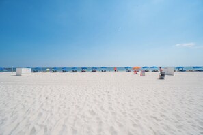 A beach with white sand, blue umbrellas, and lounge chairs. - New Listing! Stunning Renovated Beachfront 2BR/2BA • Sleeps 8• 6th-Floor (Orange Beach)