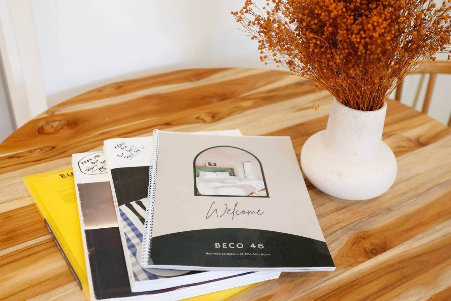 A welcome brochure for BECO 46, a hotel in Lisbon, with a photo of a room and a vase with dried flowers.