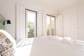 Ein helles Schlafzimmer mit einem großen Bett, einem Fenster und einem Kleiderschrank.