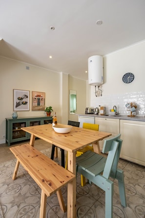 A modern kitchen with a wooden table, bench, and a water heater mounted on the wall. - Stylish Oasis in Trendy Historic Centre Quarter (Lisbon)