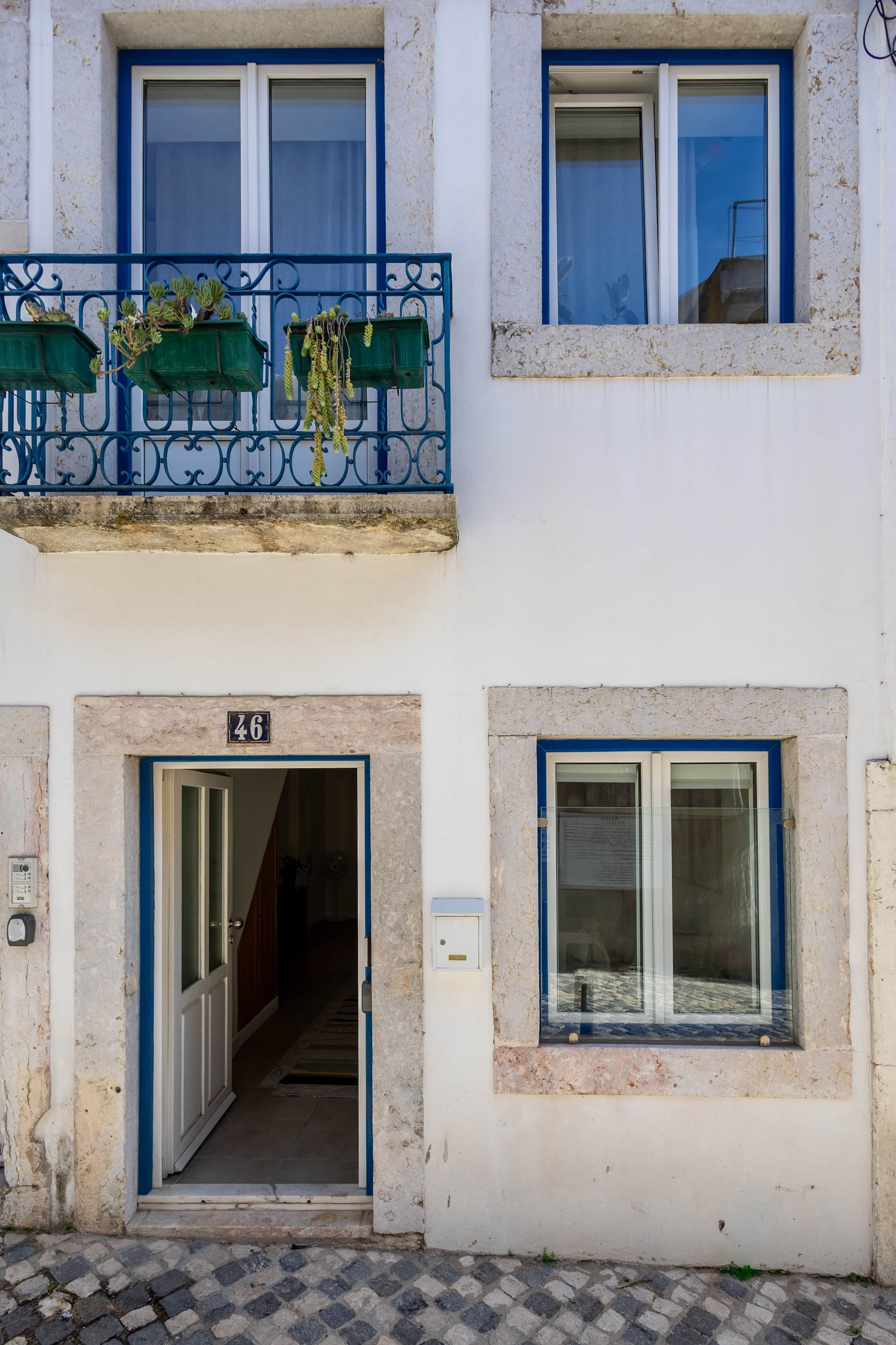 A building with a balcony, a door with a number, and a window.