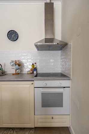 A kitchen with a stove, oven, and a wall-mounted clock. - Stylish Oasis in Trendy Historic Centre Quarter (Lisbon)