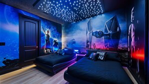 Una camera da letto con soffitto stellato, un grande affresco di una battaglia spaziale e due letti.