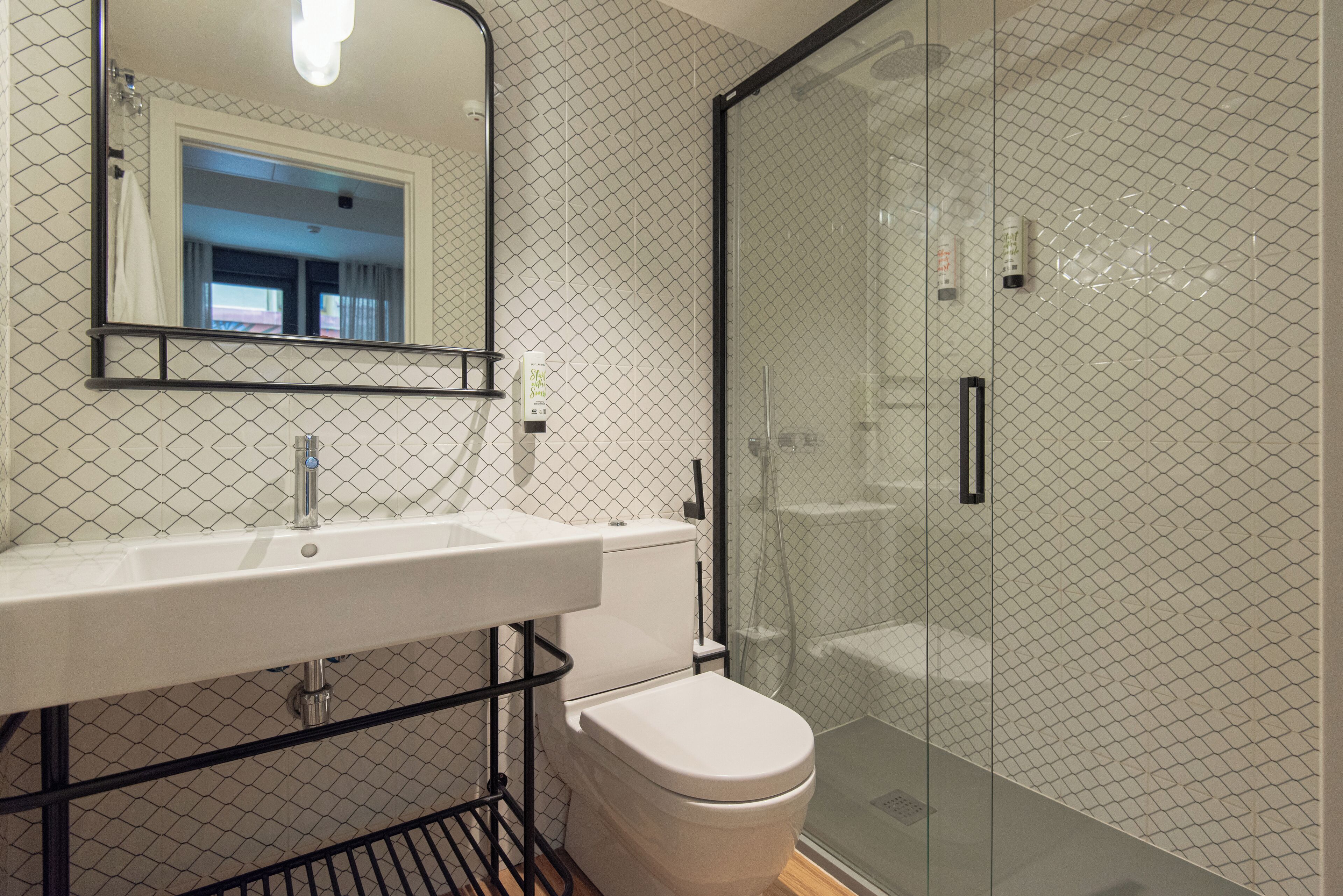 A modern bathroom with a glass shower enclosure, a white sink, and a toilet.