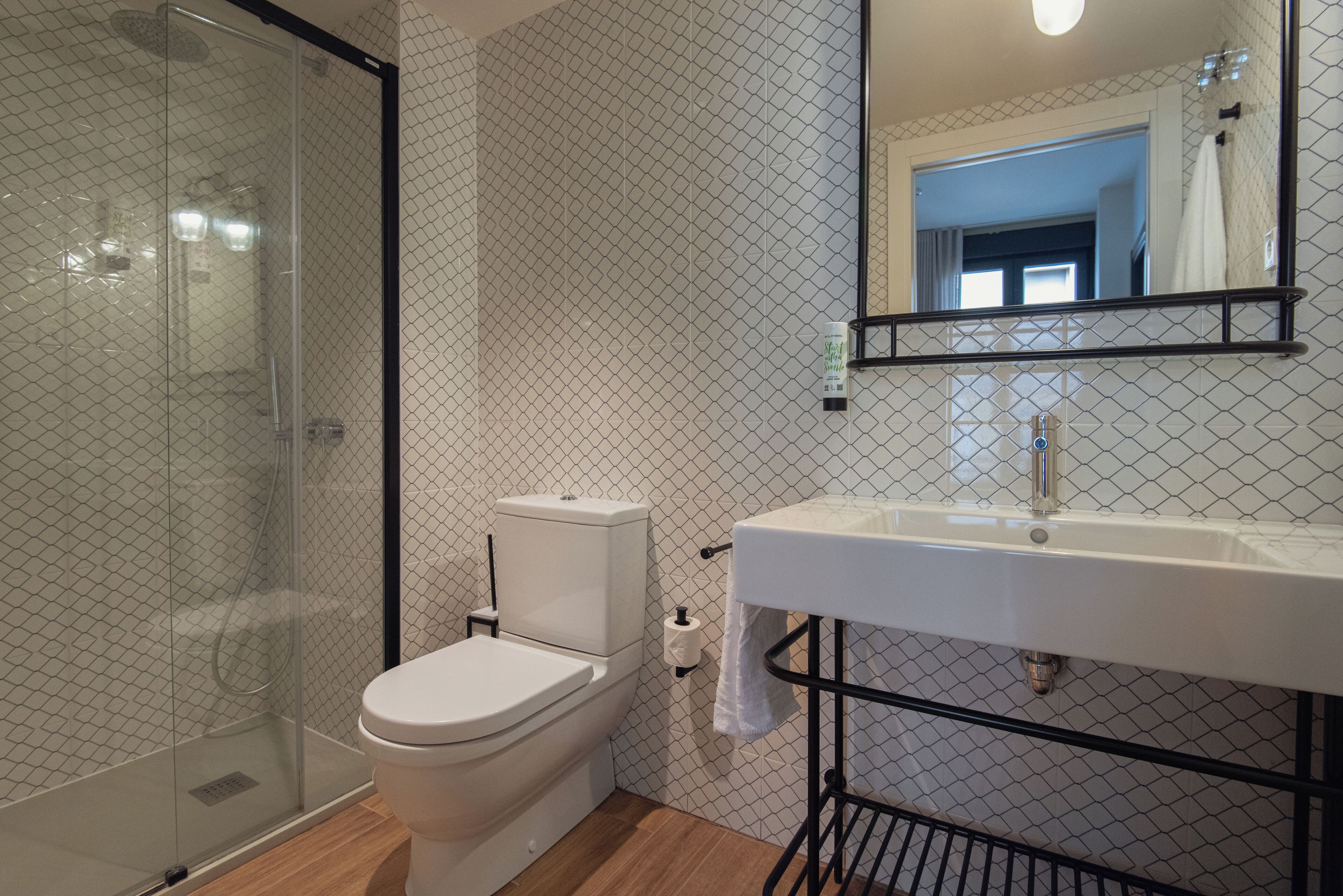 Une salle de bain moderne avec une douche à parois de verre, des toilettes et un lavabo surmonté d’un miroir.