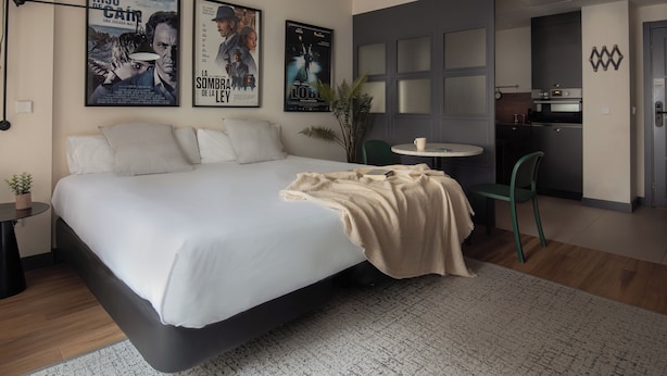 A modern hotel room with a large bed, a small round table, and a kitchenette. - Líbere Madrid Malasaña (Madrid)