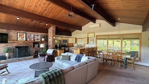 A spacious living area with a fireplace, seating, and a kitchen in the background. - Upper Villa at Holiday Valley (Ellicottville)