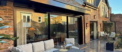 A modern house with a patio area featuring a sofa, a table, and outdoor seating.