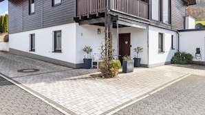 Ein modernes, zweistöckiges Gebäude mit einem Balkon, Topfpflanzen und einer Tür mit der Nummer 5.