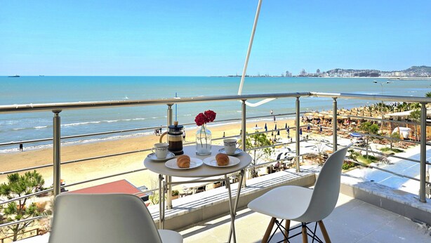 Ein Balkon mit Frühstückstisch, der Blick auf Strand und Meer freigibt.