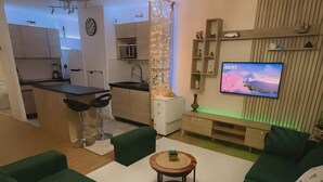 A modern living room with green sofas, a coffee table, and a TV. - Vacation Rental Apartment with Shared Garden, Balcony & Wi-Fi (Bezons)