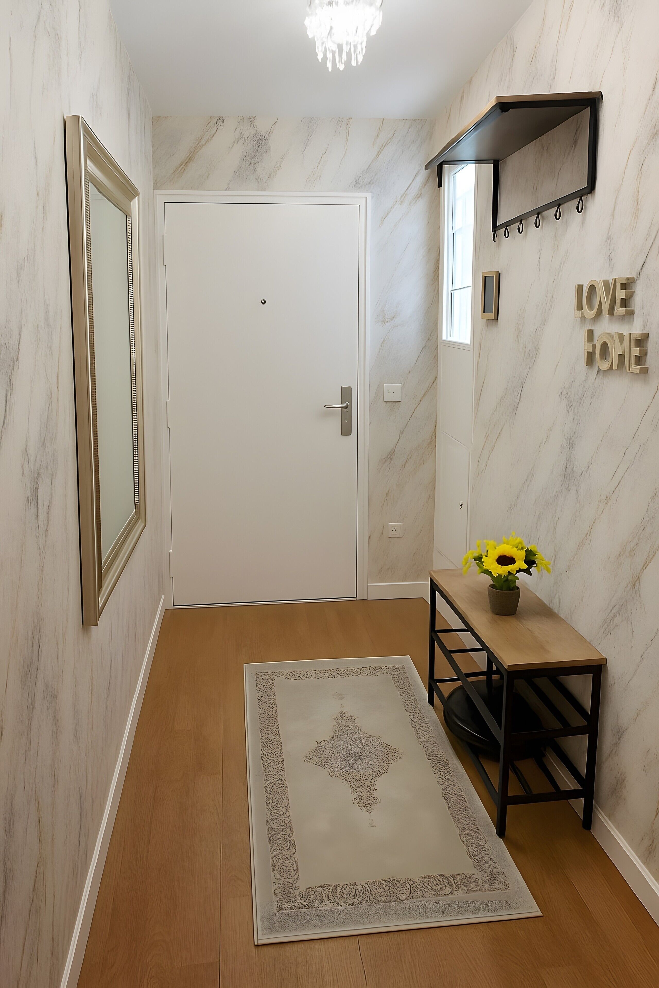 Un couloir avec une porte blanche, un miroir, une petite table sur laquelle est posé un vase rempli de tournesols, et une pancarte sur laquelle on peut lire « LOVE HOME ».