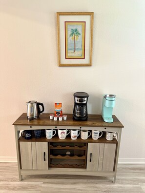 Eine Holztischstation mit Kaffeemaschine, Wasserkocher und Tassenhalterung.