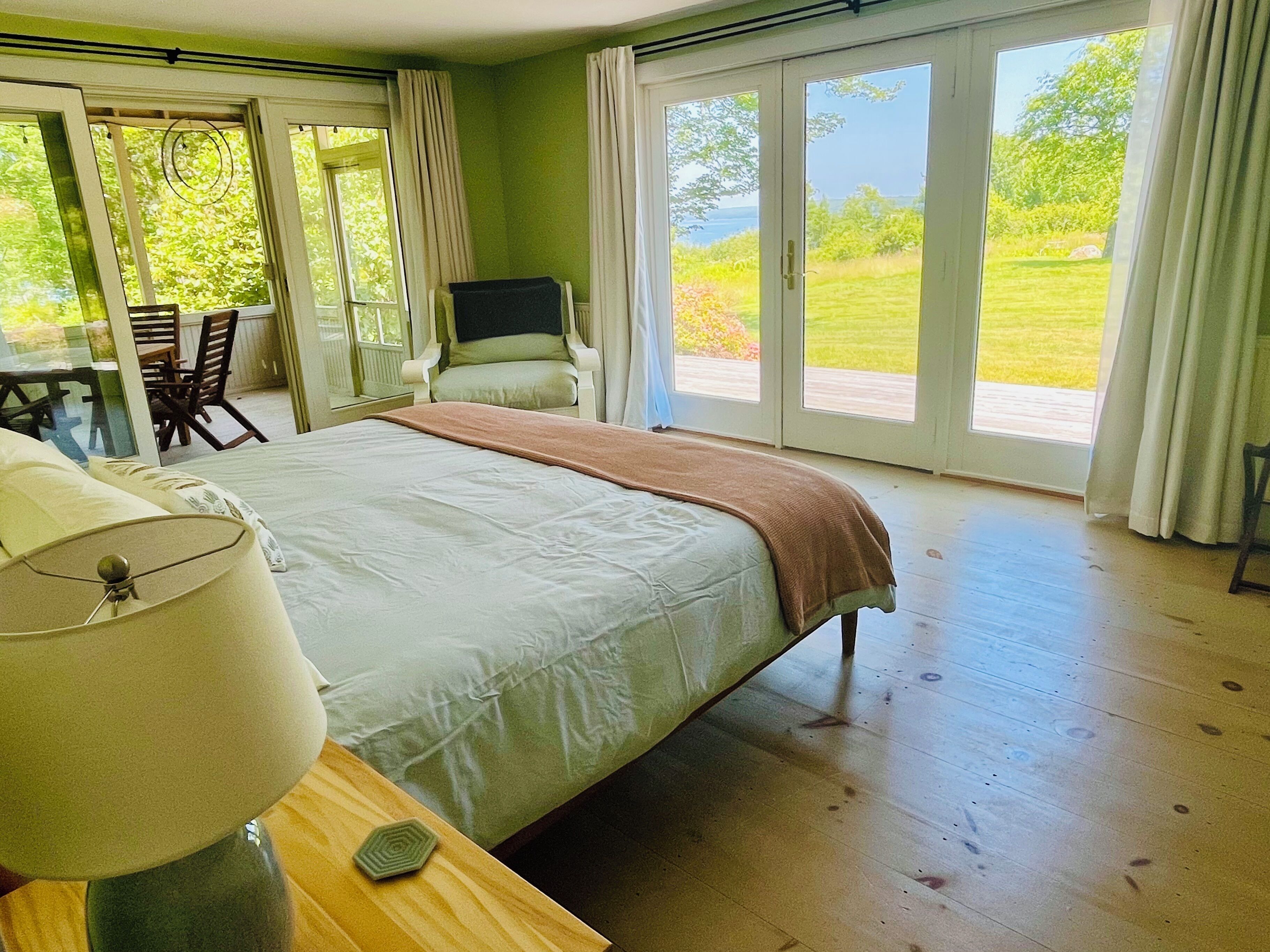 A bedroom with a bed, a chair, a table, and a TV.