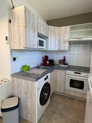 A compact kitchen with a built-in washing machine, a microwave, and a stove.
